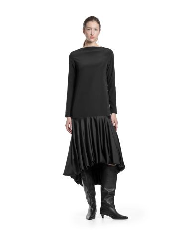 Femme en robe noire asymétrique et bottes.