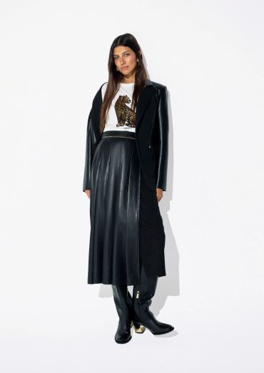 Woman in black leather skirt and long black coat with boots.