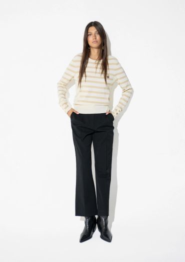 Woman in beige striped sweater and black pants.