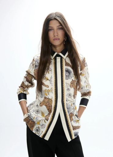 Woman wearing a patterned shirt with animal and floral designs.