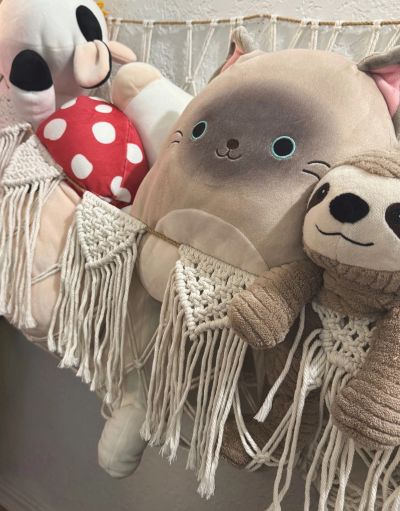 Three plush toys with macrame hammock in a cozy setting.
