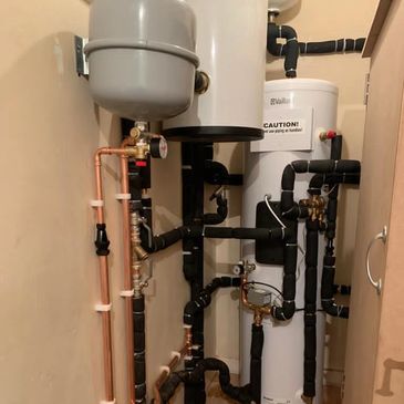 A complex water heating system with multiple pipes and a caution label.