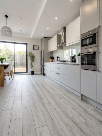 Modern kitchen with light wood flooring and sleek white cabinets.
