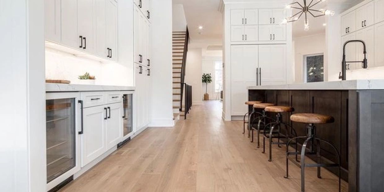 Modern kitchen with light wood flooring and white cabinetry.