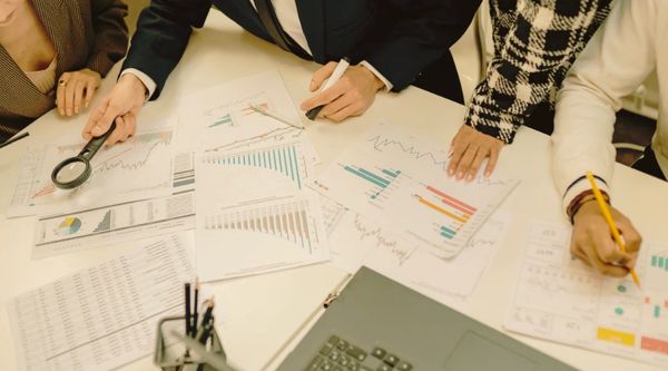 People analyzing financial charts and data during a meeting.