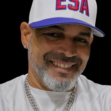 Smiling man wearing a white cap with ESA logo and diamond earrings.
