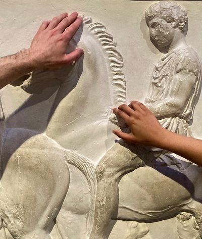 Two people feeling the touch tour of the cast in room 18B at The British Museum