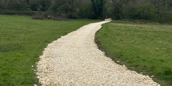 A winding gravel path cutting through green grass fields.
