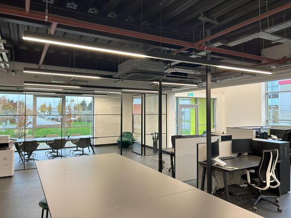 Modern office space with desks and glass meeting rooms.