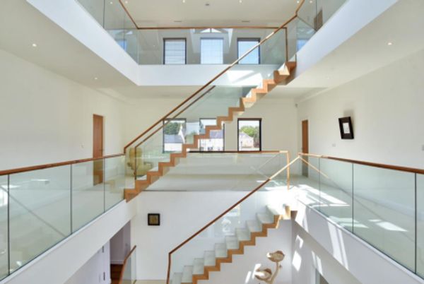 Modern staircase with glass railings and wood steps in a bright, open space.
