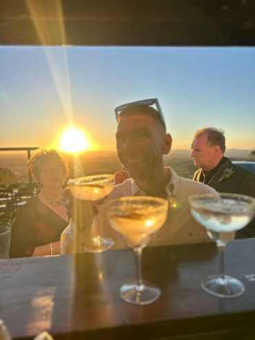 People enjoying drinks at sunset on an outdoor terrace.