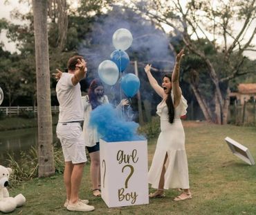 Couple celebrates as blue smoke reveals baby boy at gender reveal party.