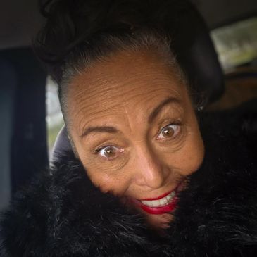 Close-up of a smiling woman with bright red lipstick and a black fur collar.