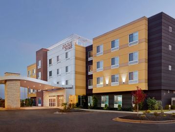 Modern four-story hotel building with a covered entrance at dusk.