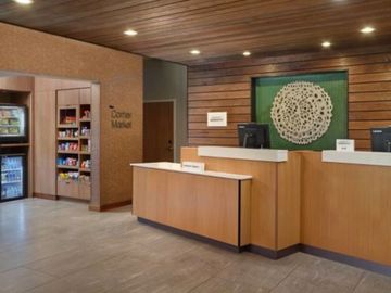 Modern hotel reception desk with wooden accents and a small market area.