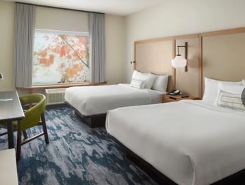 Modern hotel room with two beds and a large window.
