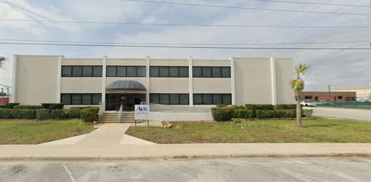 Two-story office building with a symmetrical facade and manicured bushes.