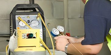 A technician using a manifold gauge set to check system pressure.