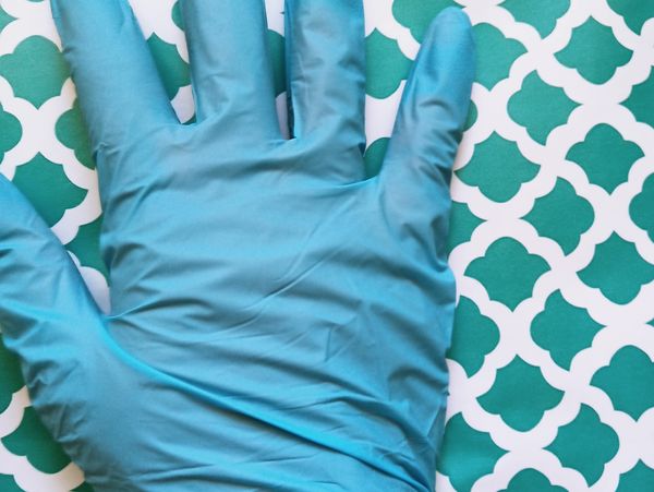 A persons hand wearing a blue nitrile glove 