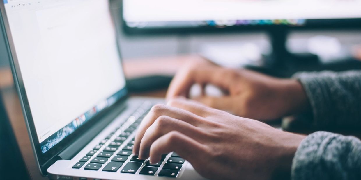 Close-up of hands typing on a laptop keyboard.