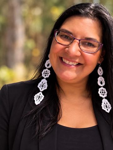 Smiling woman wearing glasses and long earrings.