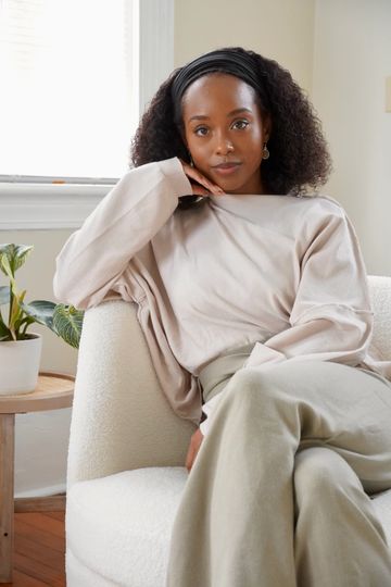 Woman sitting on a white chair indoors.