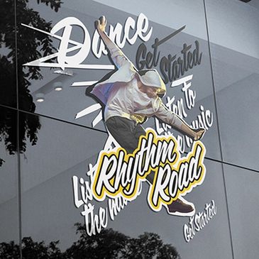 Window decal of a dancer with 'Rhythm Road' and motivational text.