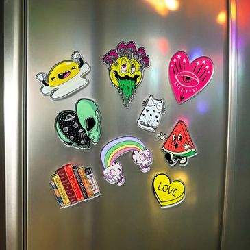 Colorful quirky magnets on a silver fridge with playful designs.