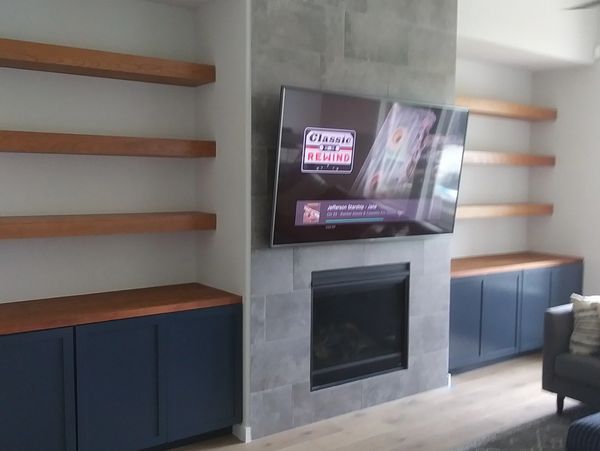 Light stained floating shelves and dark blue custom cabinets