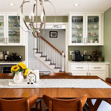 Cozy dining area with wooden table, sunflowers, and modern chandelier.