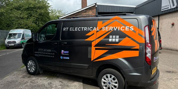 Black van with bright orange RT Electrical Services logo parked outside a building.