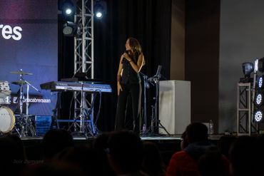 A woman speaking on stage at an event with musical instruments nearby.