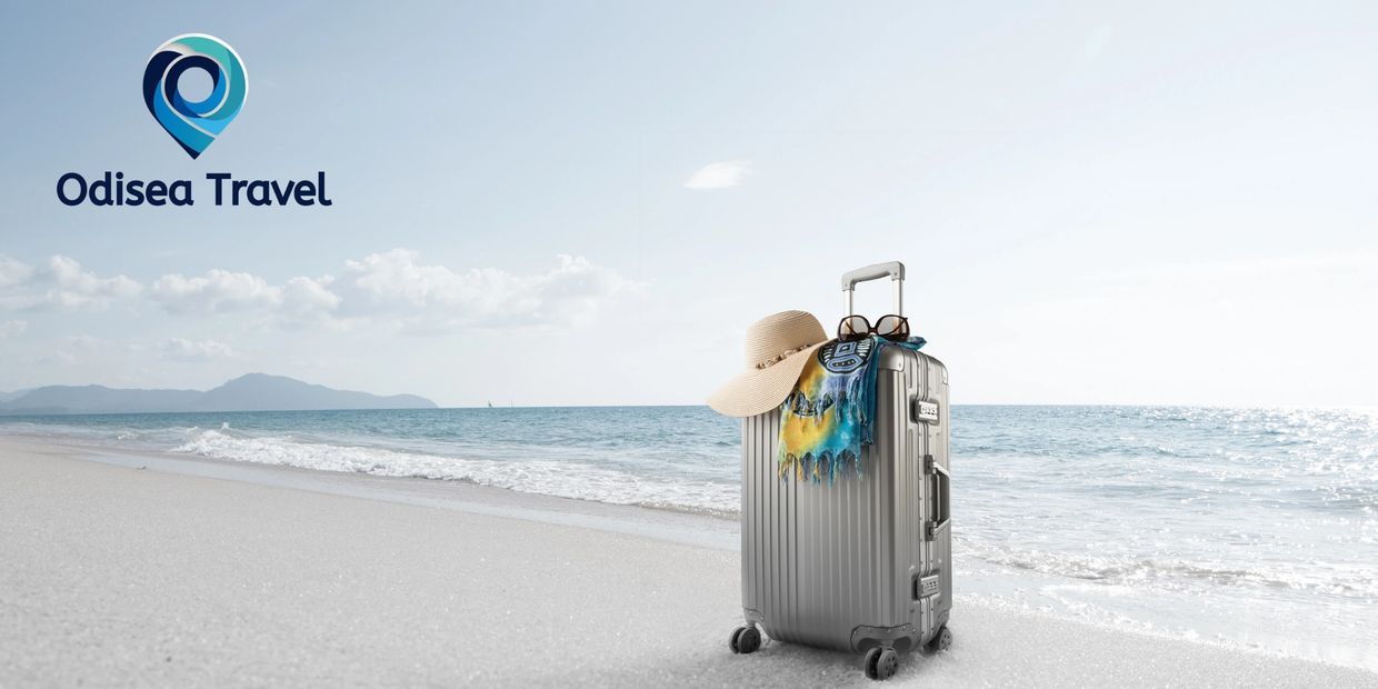 Silver suitcase with travel accessories on a serene beach, Odisea Travel logo in the sky.