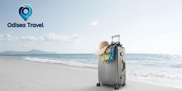 Silver suitcase with travel accessories on a serene beach, Odisea Travel logo in the sky.