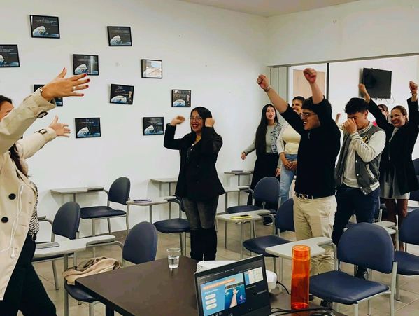 People in a classroom raising their arms, appearing happy and engaged.
