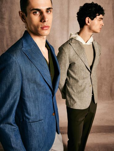 Two men in stylish blazers posing against a neutral backdrop.