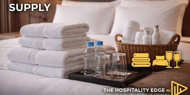 Hotel bed with towels, water bottles, and toiletries.