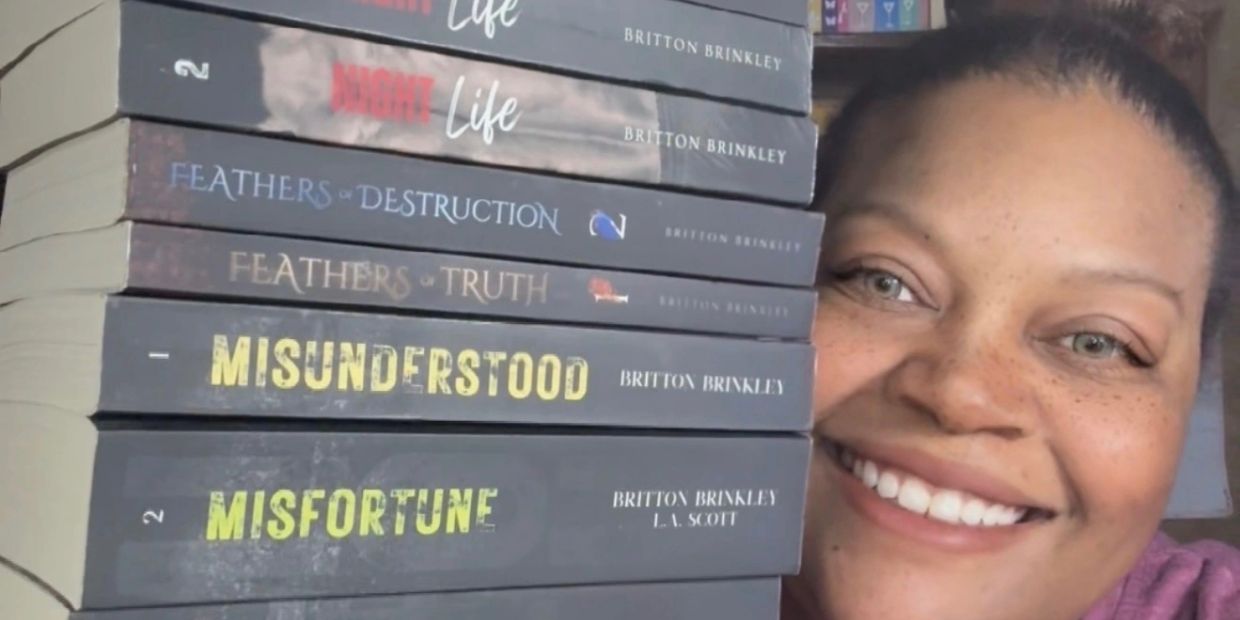 Woman smiling with a stack of books by Britton Brinkley.