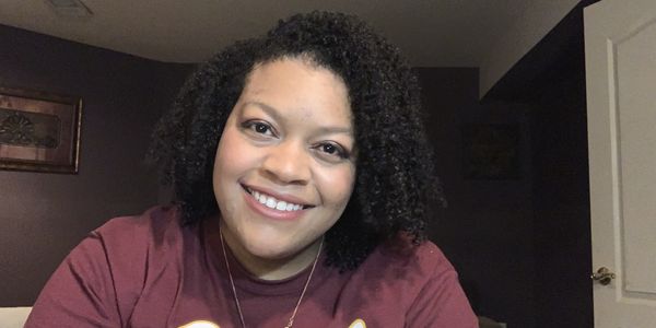 Woman with curly hair smiling indoors.