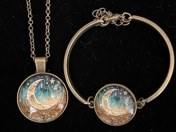 A matching moon and stars pendant necklace and bracelet set on black background.