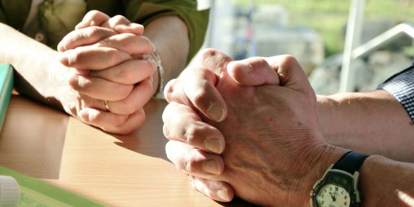 Two people with clasped hands on a table.