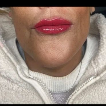 Close-up of lips with glossy red lipstick and cozy white fleece jacket.