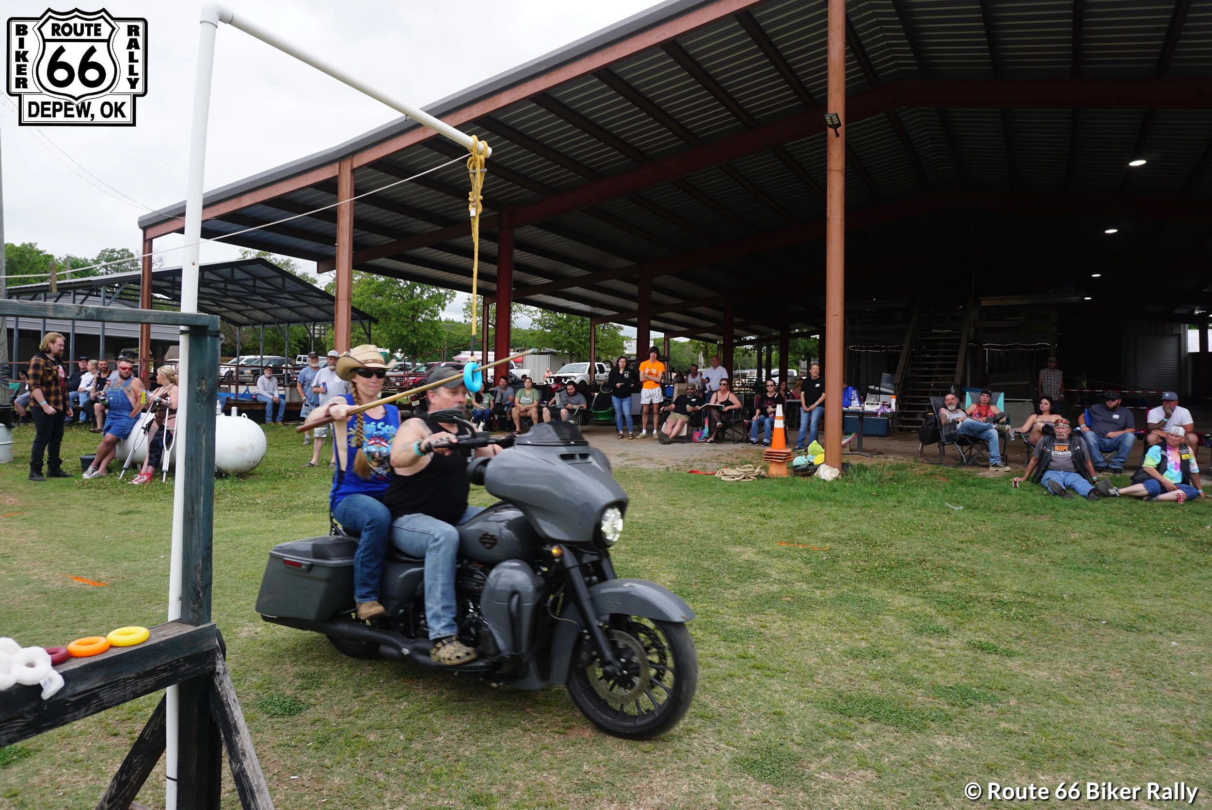 Two riders on a motorcycle playing ring toss at Route 66 Biker Rally.