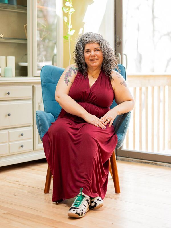 A woman in a burgundy dress sitting on a blue chair indoors.