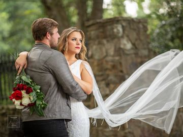 Sexy bride and groom. Veil flying photo. Fresh flowers  with red and white roses. White Raven Manor