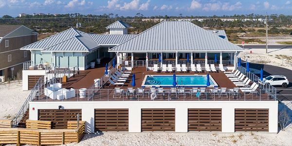 Beachside resort with pool and lounge chairs under blue sky.