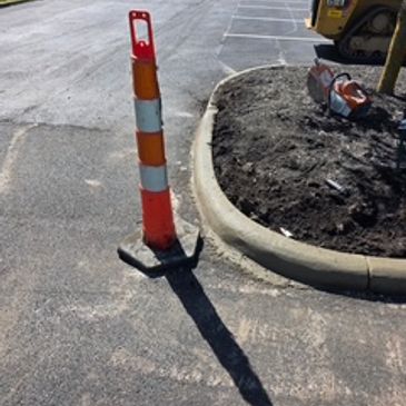 Orange traffic cone next to a newly curved sidewalk.