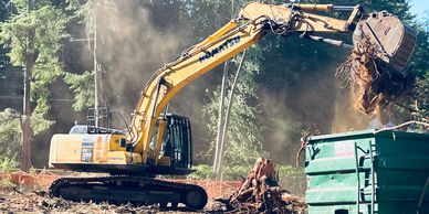 excavator loading tree stumps in a bin