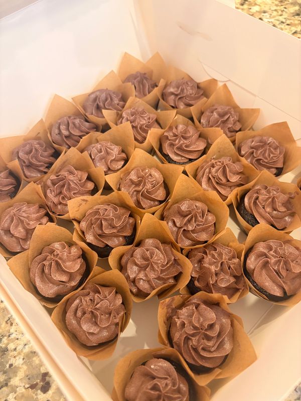 Box of chocolate cupcakes with swirled frosting in brown wrappers.