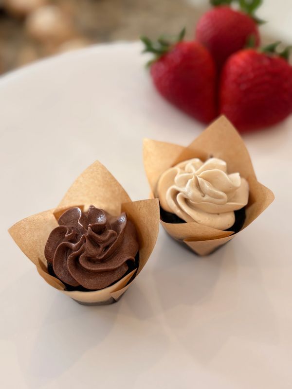 Two cupcakes with chocolate and vanilla frosting, garnished with strawberries.
